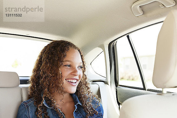 Glücklicher Teenager schaut weg  während er im Auto sitzt