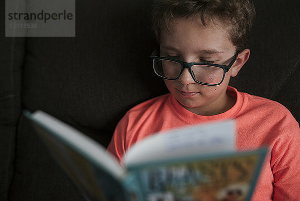 Nahaufnahme eines Jungen  der eine Brille trägt  während er zu Hause auf dem Sofa lernt