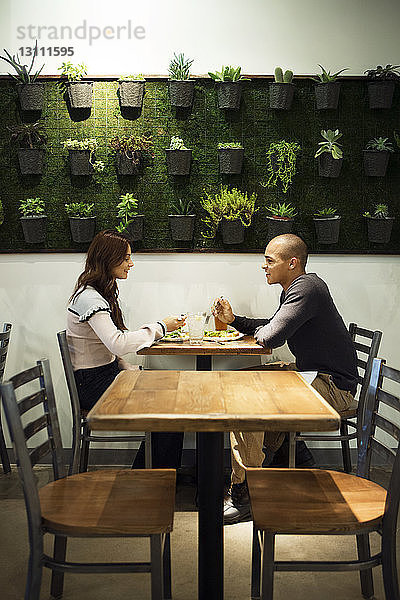 Seitenansicht eines Paares  das sich beim Essen im Restaurant unterhält