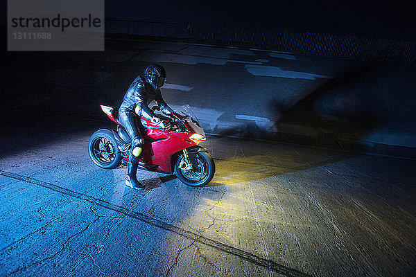 Motorradfahrer mit Motorrad nachts auf der Straße