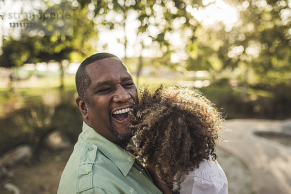 Hochwinkelansicht eines glücklichen Vaters  der seinen Sohn umarmt  während er im Park steht