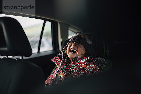 Fröhliches Mädchen lacht  während sie im Auto sitzt