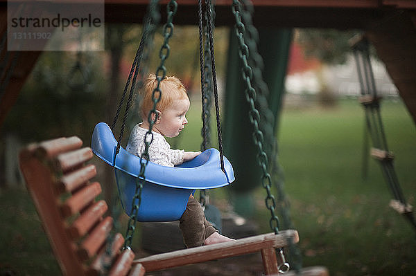 Süßer kleiner Junge schaukelt im Park