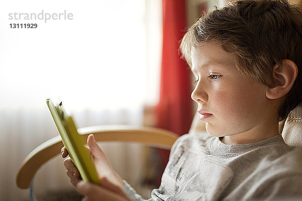 Junge benutzt Tablet-Computer  während er zu Hause sitzt