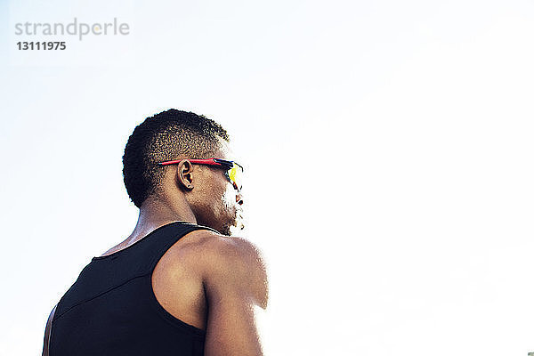Niedrigwinkelansicht eines männlichen Sportlers mit Sonnenbrille bei klarem Himmel