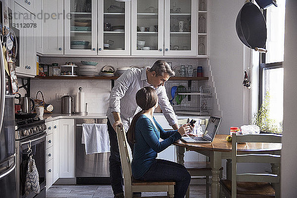 Ehepaar betrachtet Laptop-Computer in der Küche