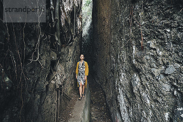 Frau geht inmitten von Felsformationen im Wald