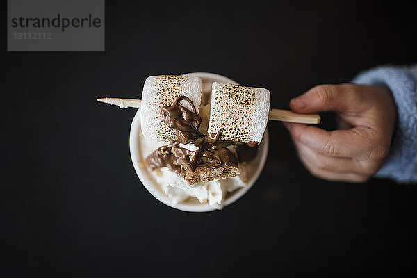 Abgehackte Hand eines Mädchens mit Marshmallow in der Hand