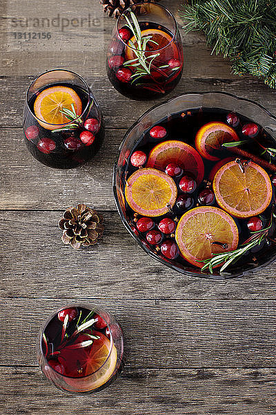 Hochwinkelansicht von Getränken mit Früchten und Tannenzapfen auf Holztisch
