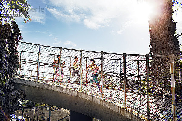 Joggerinnen auf der Brücke gegen den Himmel an einem sonnigen Tag