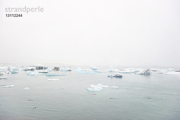 Szenische Ansicht von auf dem Meer treibenden Eisbergen bei klarem Himmel