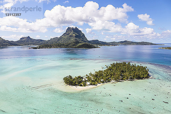 Landschaftliche Ansicht der Insel Bora Bora bei bewölktem Himmel am sonnigen Tag