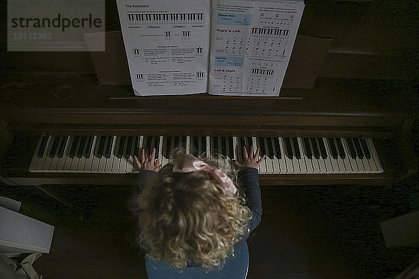 Hochwinkelaufnahme eines zu Hause Klavier spielenden Mädchens