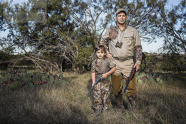 Porträt von Jägern mit Gewehr in der Hand auf einem Grasfeld stehend