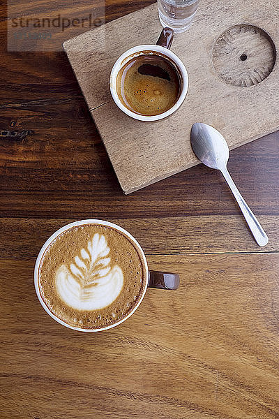Draufsicht auf Kaffeetassen auf Holztisch im Café