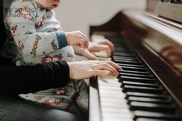 Mittelteil einer Mutter mit Sohn  die zu Hause Klavier spielt
