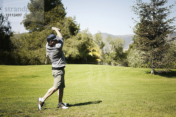 Mann schwingt Golfschläger auf dem Golfplatz