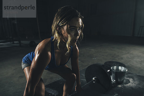 Selbstbewusste Athletin beim Langhantelheben im Fitnessstudio