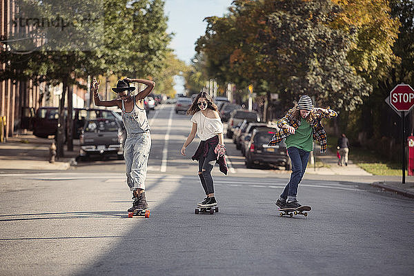 Freunde in voller Länge beim Skateboarden auf der Straße