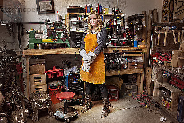 Porträt einer selbstbewussten Mechanikerin mit Schürze in der Werkstatt