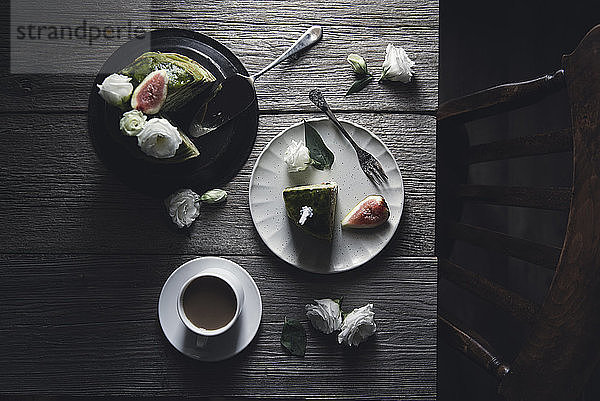 Draufsicht auf Pfannkuchen mit Kaffee und Rosen auf Holztisch