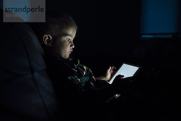 Seitenansicht eines Jungen mit Tablet-Computer in der Dunkelkammer