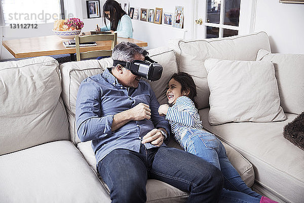 Spielerischer Vater trägt einen Virtual-Reality-Simulator  während er mit seiner Tochter zu Hause spielt