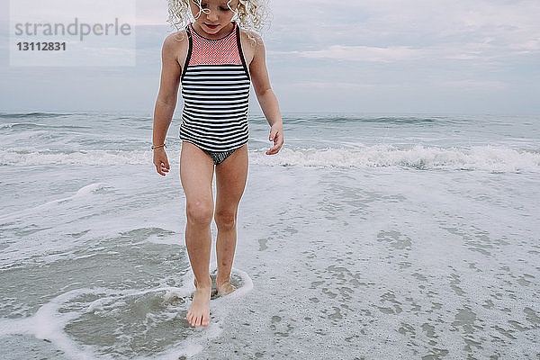 Mädchen spielt in Wellen am Cape May Beach gegen den Himmel