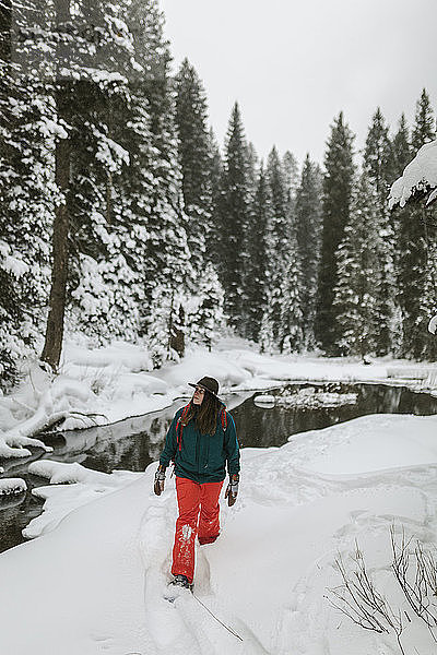 Frau geht auf schneebedecktem Feld im Wald