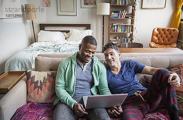 Hochwinkelansicht von homosexuellen Männern mit Laptop auf dem Sofa zu Hause