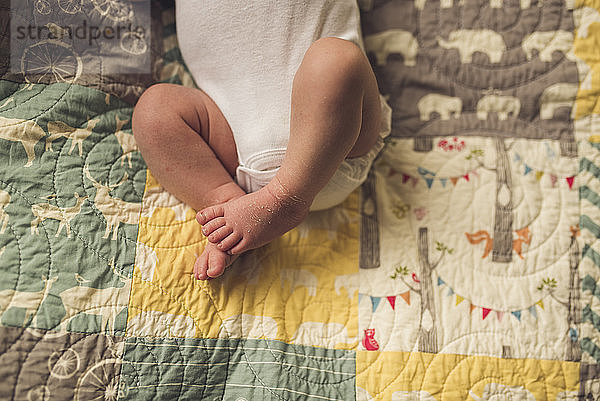 Niedere Sektion eines neugeborenen Jungen  der zu Hause auf dem Bett liegt