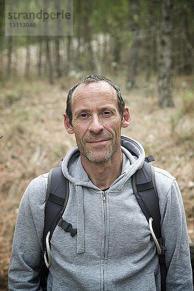 Porträt eines selbstbewussten Wanderers mit Kapuzenjacke im Wald