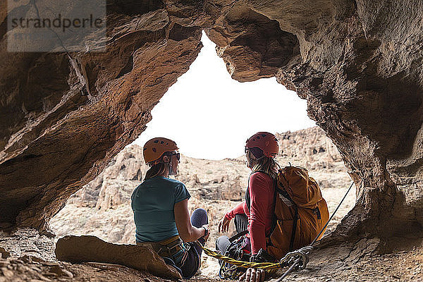 Weibliche Wanderer sitzen am Eingang der Höhle in einer Felsformation
