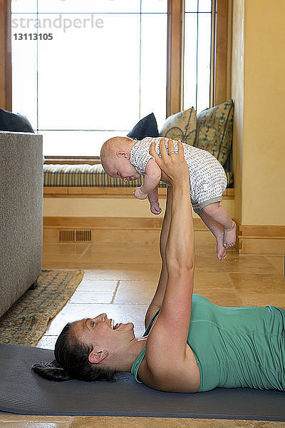 Seitenansicht einer fröhlichen Mutter  die mit ihrer Tochter zu Hause auf der Gymnastikmatte trainiert
