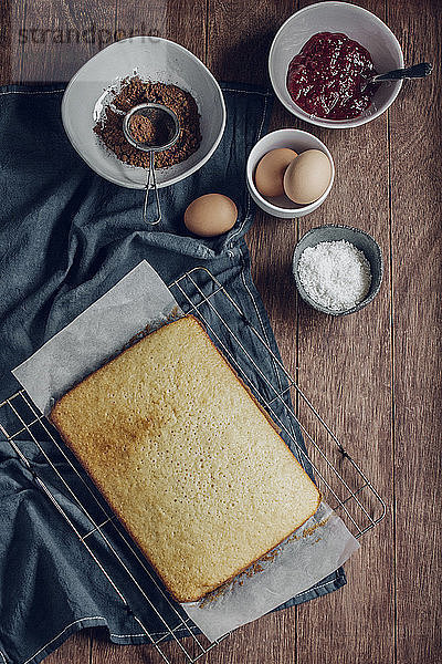 Draufsicht auf frisch gebackenen Kuchen und Zutaten auf Holztisch