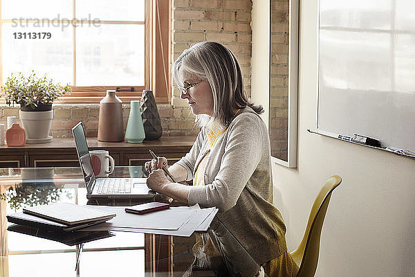 Seitenansicht einer reifen Geschäftsfrau mit Laptop im Kreativbüro