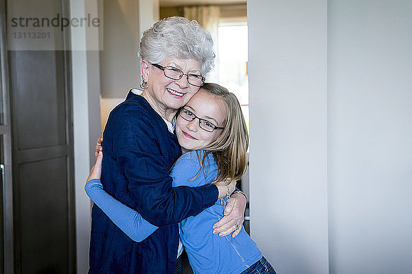 Porträt einer Enkelin  die ihre Großmutter zu Hause umarmt