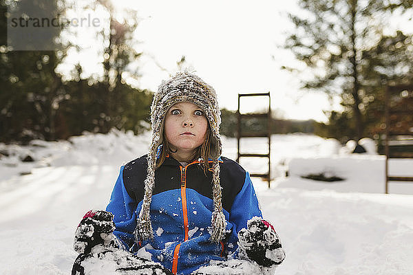 Porträt eines Mädchens auf schneebedecktem Feld sitzend