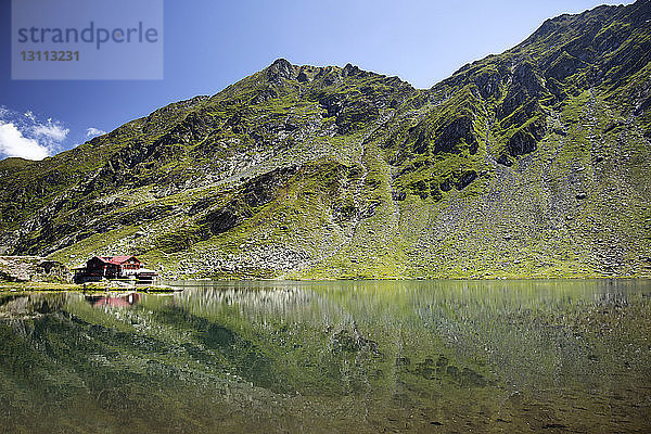 Spiegelung von Haus und Berg im See gegen den Himmel