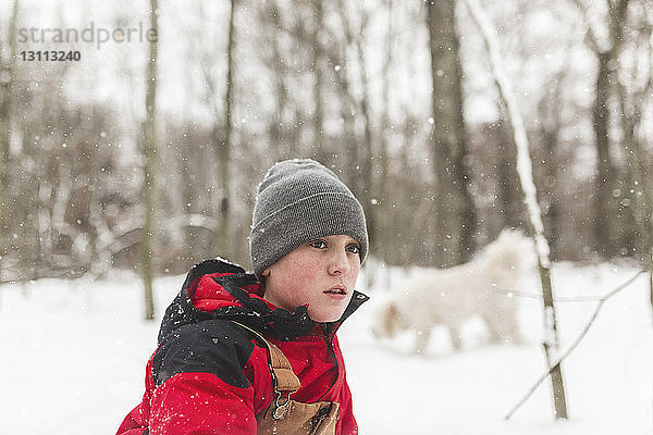 Seitenansicht eines Teenagers  der im Winter im Wald steht und dabei wegschaut