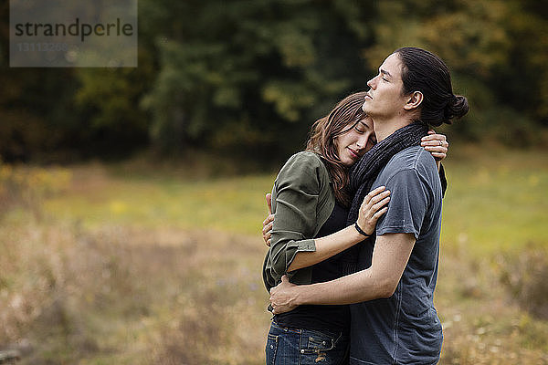 Paar umarmt sich  während es auf einem Grasfeld steht