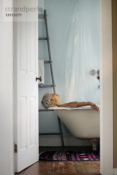 Seitenansicht einer Frau  die sich zu Hause in der Badewanne entspannt