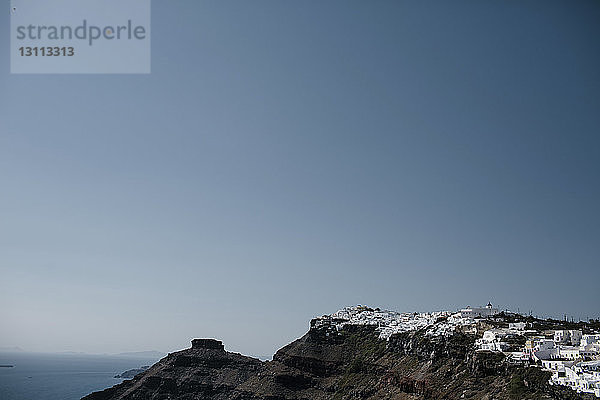 Weiß getünchte Häuser in der Stadt auf Bergen gegen klaren Himmel am Meer