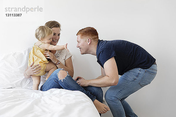 Glückliche Eltern spielen mit der Tochter im Schlafzimmer
