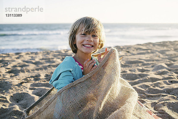 Porträt eines Mädchens  das in einem Sack am Strand sitzt