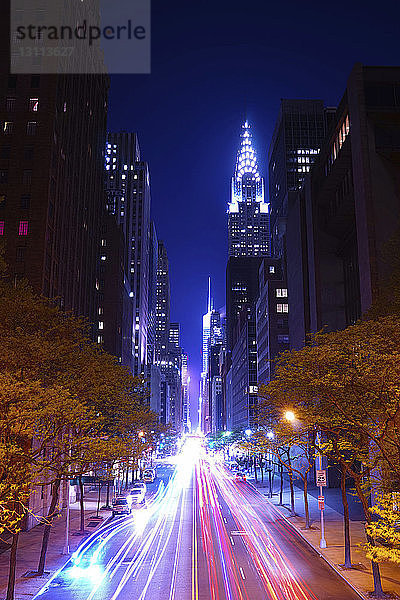 Lichtspuren auf der Straße durch beleuchtete Gebäude bei Nacht
