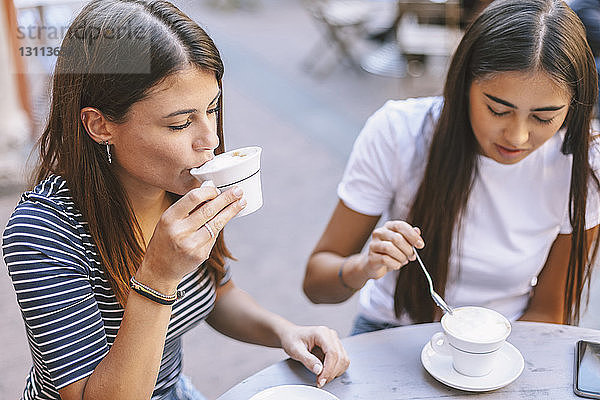 Schrägaufnahme von Freunden  die Cappuccino trinken  während sie im Straßencafé sitzen