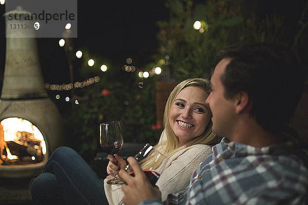 Paar mit Weingläsern sitzt auf dem Sofa auf der Terrasse