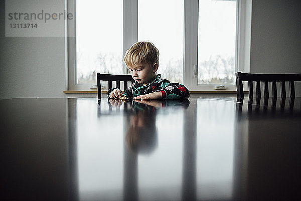 Junge spielt mit Spielzeug auf dem Tisch  während er zu Hause sitzt