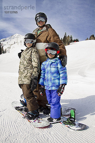 Vater und Sohn stehen auf Snowboards auf schneebedecktem Berg